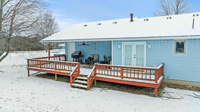 snow covered rear of property with a wooden deck and a ceiling fan