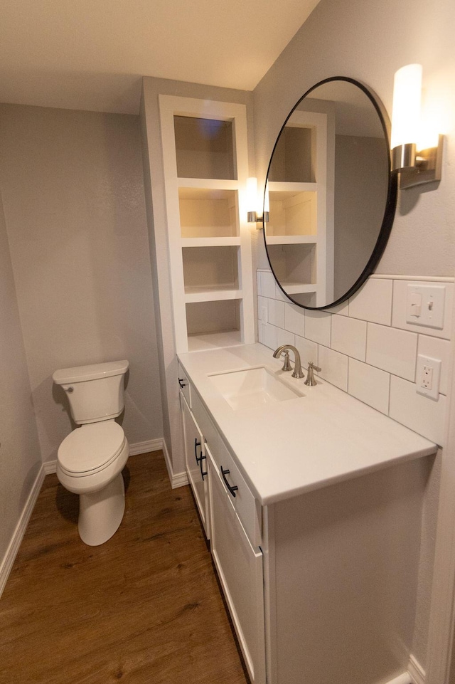 912 Armstrong Ave, West Plains, MO 65775 - bathroom with wood finished floors, toilet, vanity, baseboards, and decorative backsplash