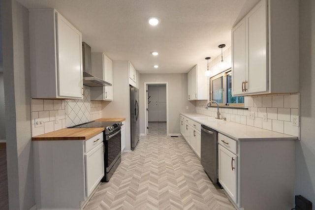 912 Armstrong Ave, West Plains, MO 65775 - kitchen with wall chimney range hood, a sink, butcher block counters, baseboards, and appliances with stainless steel finishes