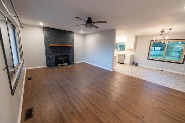912 Armstrong Ave, West Plains, MO 65775 - unfurnished living room with ceiling fan with notable chandelier, a stone fireplace, wood finished floors, and recessed lighting