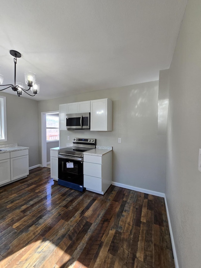 kitchen featuring dark wood-style flooring, hanging light fixtures, stainless steel appliances, light countertops, and white cabinetry