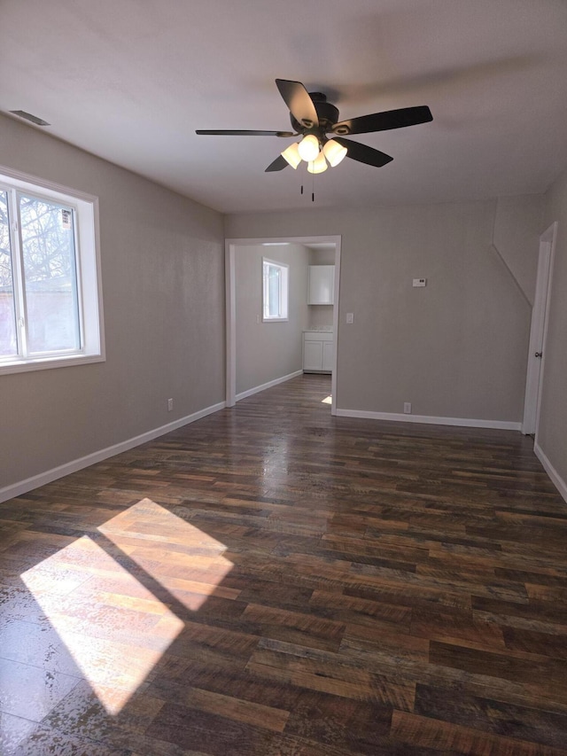 unfurnished room with dark wood-type flooring, a healthy amount of sunlight, ceiling fan, and baseboards