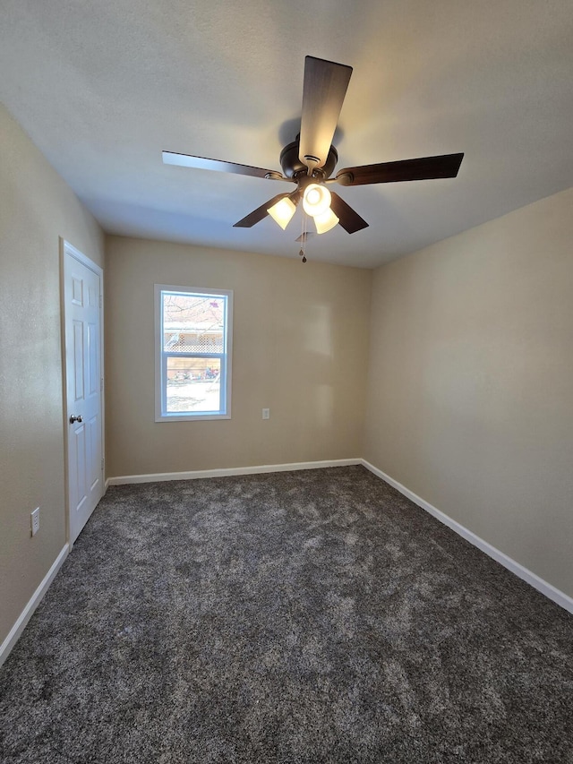 unfurnished room featuring baseboards, dark carpet, and ceiling fan