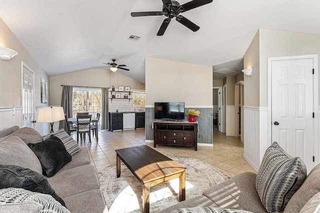 living area with a wainscoted wall, light tile patterned flooring, lofted ceiling, and visible vents