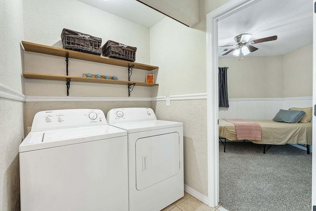 clothes washing area featuring a wainscoted wall, light tile patterned floors, a ceiling fan, laundry area, and independent washer and dryer