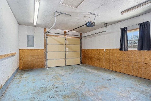 garage with a garage door opener, wainscoting, and electric panel