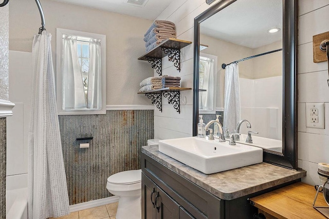 bathroom with tile patterned flooring, wainscoting, plenty of natural light, and toilet