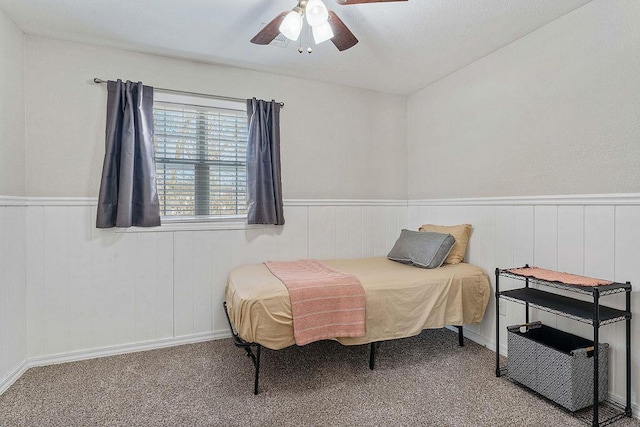 bedroom featuring a wainscoted wall, carpet flooring, and a ceiling fan