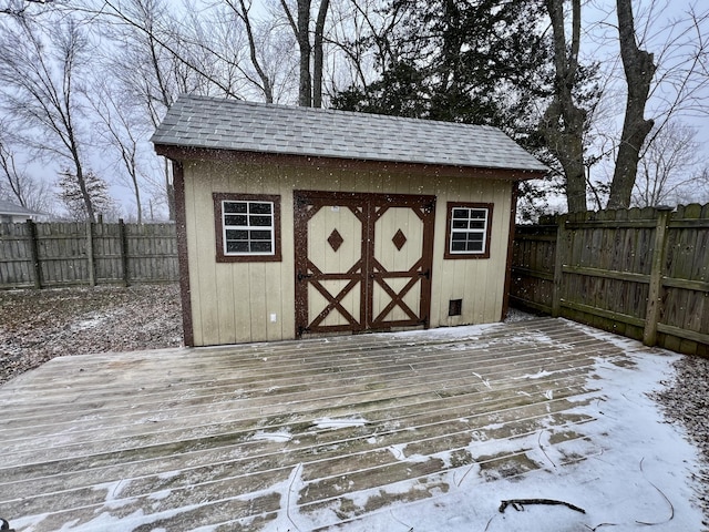 snow covered structure featuring an outbuilding, a storage unit, and a fenced backyard