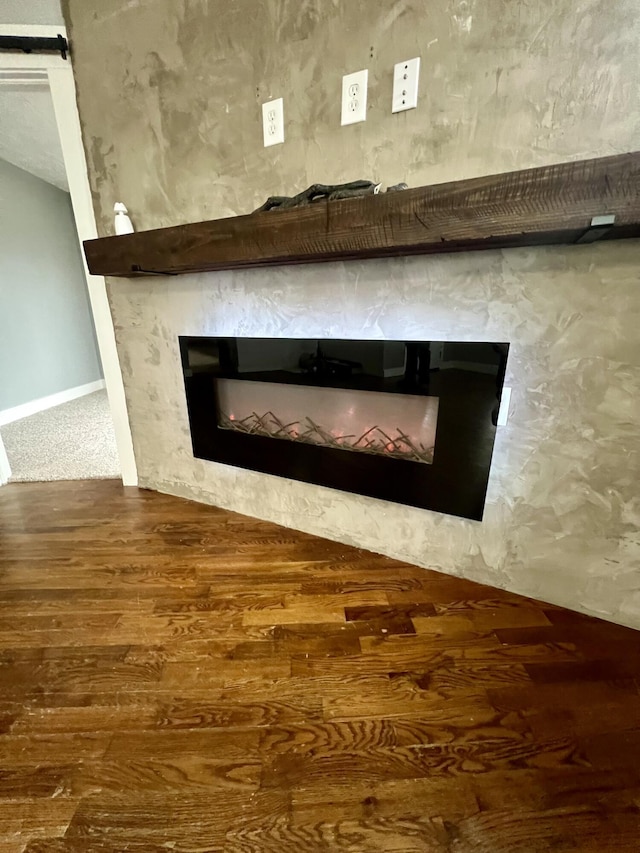 interior details with a glass covered fireplace, baseboards, and wood finished floors