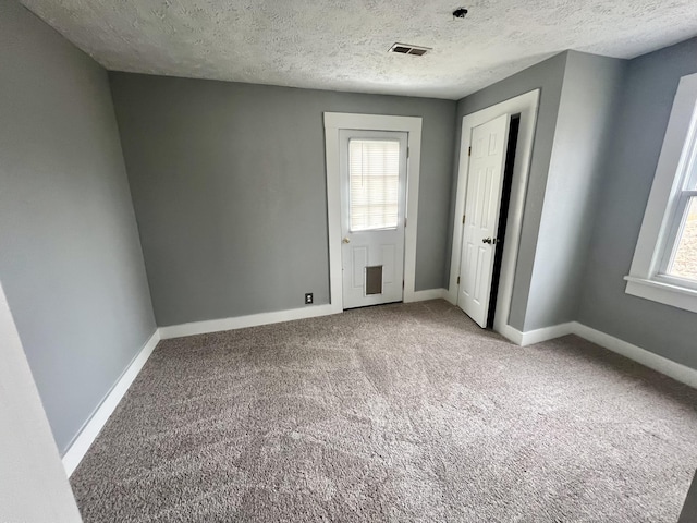 empty room featuring carpet floors, a wealth of natural light, visible vents, and baseboards