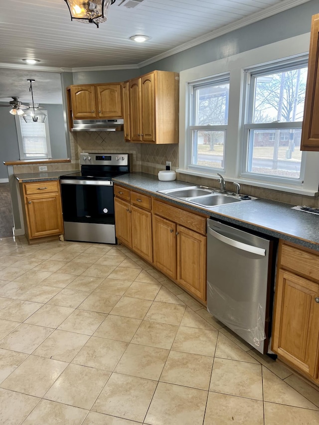 kitchen featuring dark countertops, appliances with stainless steel finishes, brown cabinets, under cabinet range hood, and a sink