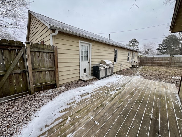 snow covered deck with fence and a grill