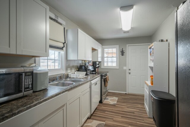 kitchen with baseboards, visible vents, dark wood-style flooring, a sink, and stainless steel appliances