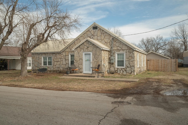 view of front of property with fence, stone siding, and a chimney