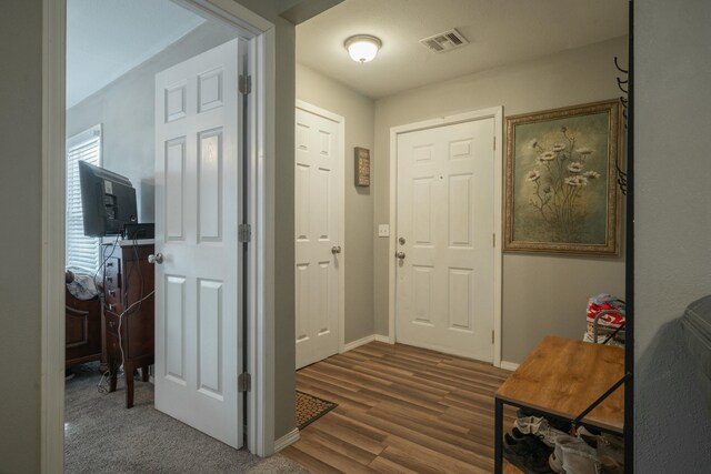 foyer with wood finished floors, visible vents, and baseboards