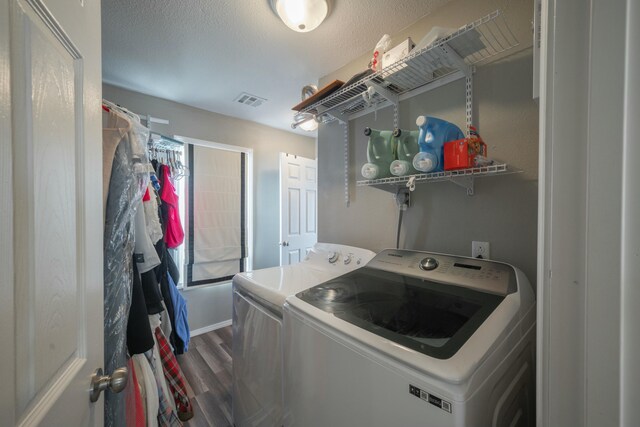 laundry room with visible vents, washing machine and clothes dryer, dark wood finished floors, laundry area, and a textured ceiling