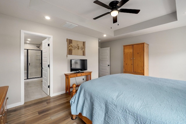 bedroom featuring a tray ceiling, recessed lighting, visible vents, wood finished floors, and baseboards