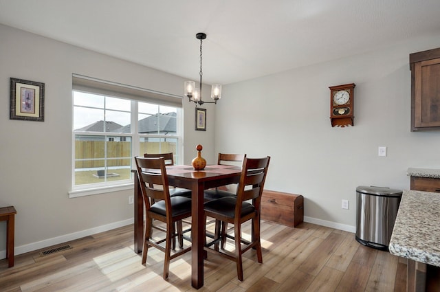 dining area with light wood-type flooring, visible vents, a notable chandelier, and baseboards