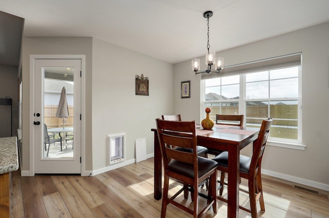 dining space with light wood-style floors, visible vents, and baseboards