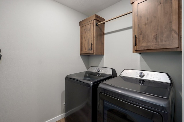 laundry room with washing machine and dryer, cabinet space, and baseboards