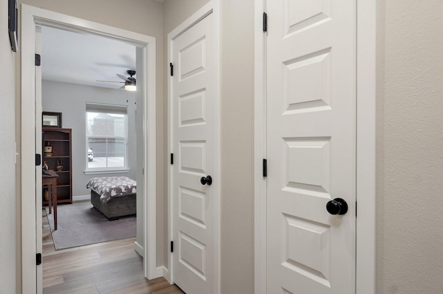 hall featuring light wood-type flooring and baseboards