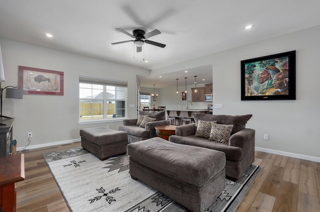 living area with wood finished floors, a ceiling fan, and baseboards