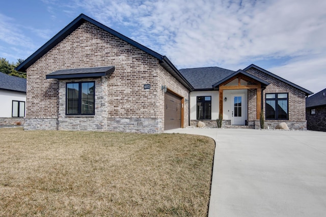 view of front of property featuring a garage, concrete driveway, brick siding, and a front yard