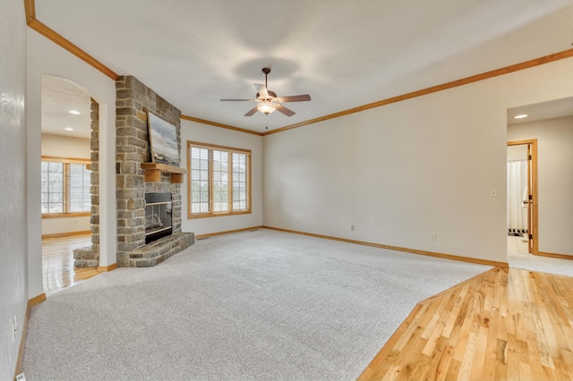 unfurnished living room featuring a large fireplace, crown molding, baseboards, and a wealth of natural light