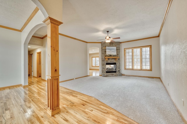 unfurnished living room with baseboards, ceiling fan, wood finished floors, a textured ceiling, and a brick fireplace