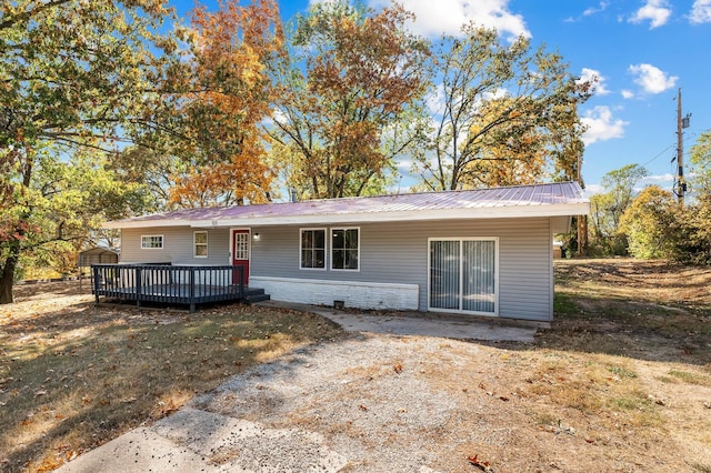 single story home featuring a front lawn, metal roof, and a wooden deck