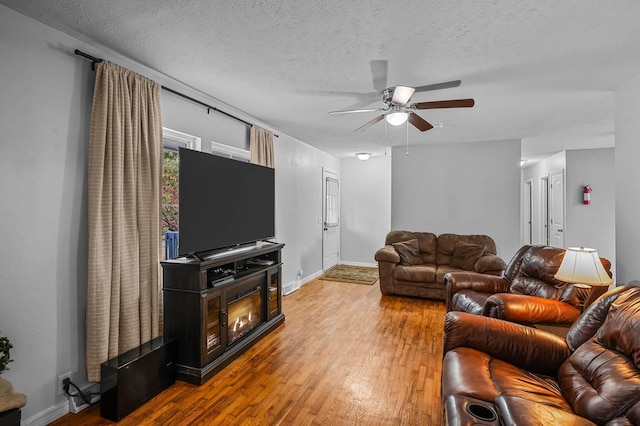 living area featuring a textured ceiling, wood finished floors, and baseboards