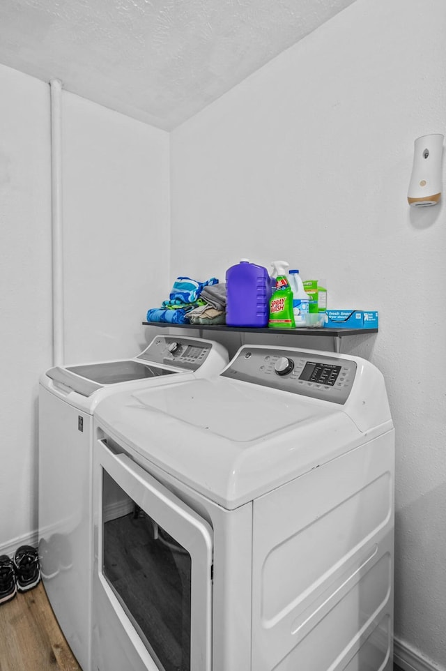 washroom with laundry area, baseboards, wood finished floors, a textured ceiling, and separate washer and dryer