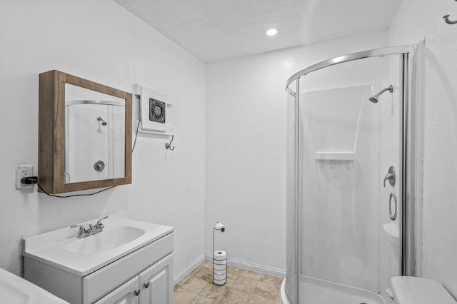 bathroom featuring a stall shower, vanity, and baseboards