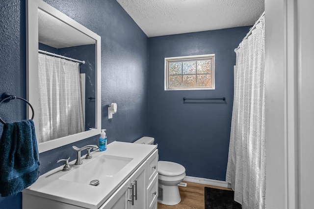 bathroom featuring a textured ceiling, toilet, wood finished floors, vanity, and baseboards