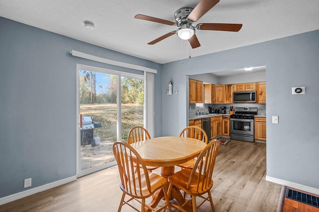 dining area with light wood-type flooring, a textured ceiling, and baseboards