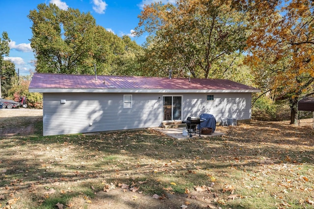 back of property featuring a patio area, metal roof, and a yard