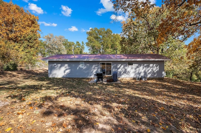 back of property with metal roof, a lawn, and a patio