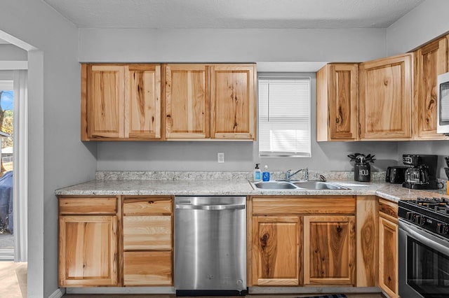 kitchen featuring stainless steel appliances, light countertops, a sink, and a textured ceiling