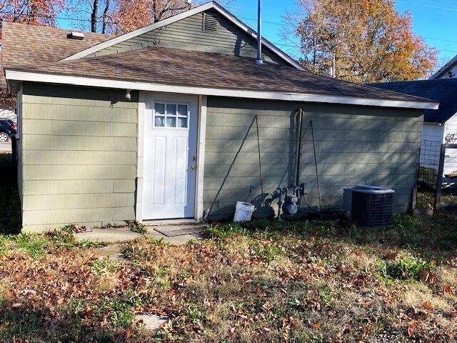 back of property featuring central AC and roof with shingles