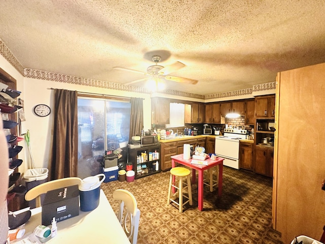 kitchen featuring dark floors, stainless steel microwave, brown cabinets, light countertops, and white range with electric cooktop