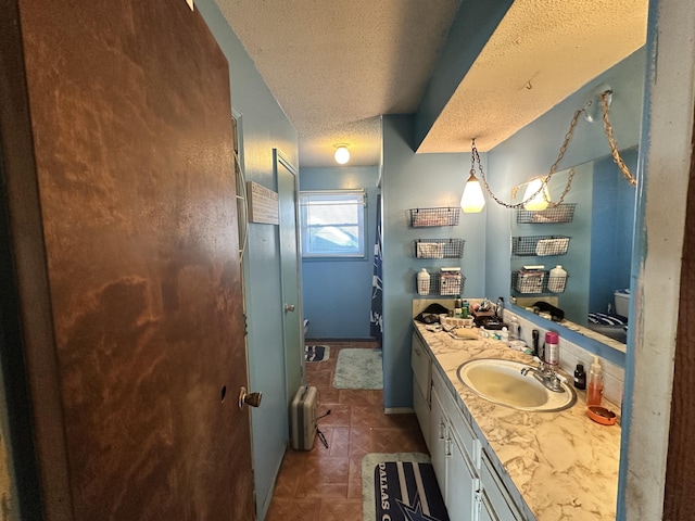 bathroom featuring baseboards, a textured ceiling, and vanity