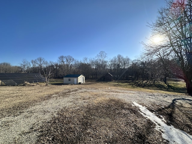 view of yard featuring a shed, a rural view, and an outbuilding