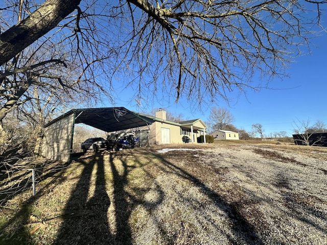 view of home's exterior with dirt driveway and a chimney