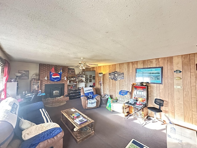 living room featuring a textured ceiling, wooden walls, carpet flooring, a ceiling fan, and a wood stove