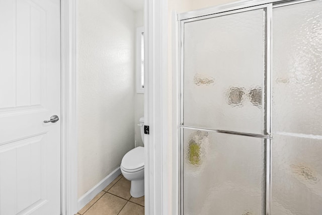 full bath featuring a stall shower, baseboards, toilet, and tile patterned floors