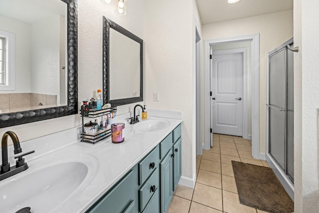 bathroom with a shower stall, double vanity, a sink, and tile patterned floors