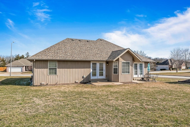 rear view of property with board and batten siding, french doors, a lawn, and roof with shingles