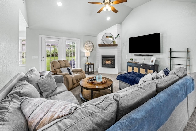 living room featuring lofted ceiling, a large fireplace, carpet floors, a ceiling fan, and baseboards