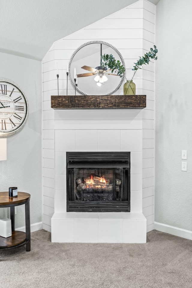 interior details featuring a ceiling fan, carpet, a fireplace, and a textured ceiling